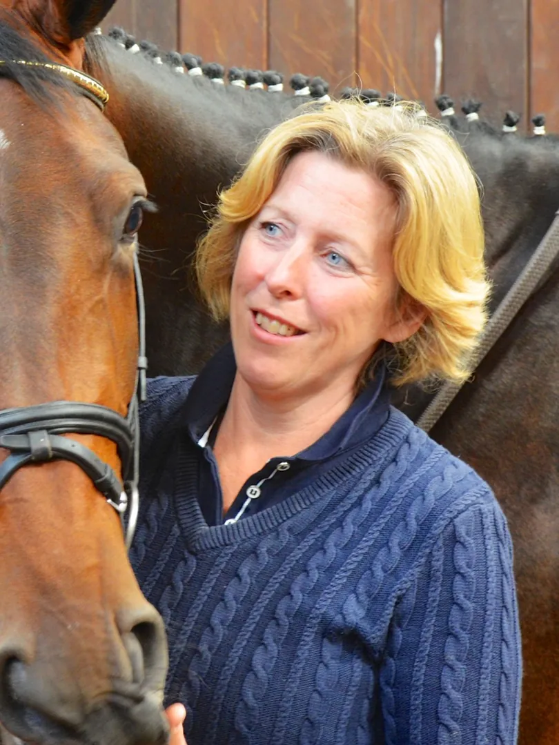 Alison Haste smiling, standing beside a bay horse