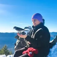 Shayla Harris outdoors in the snow, with a bird perched on her hand